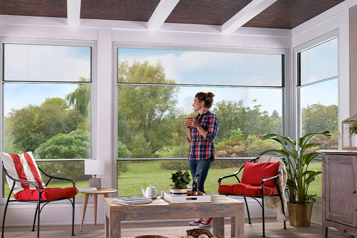 A glass sunroom with a woman looking out the window enjoying the view